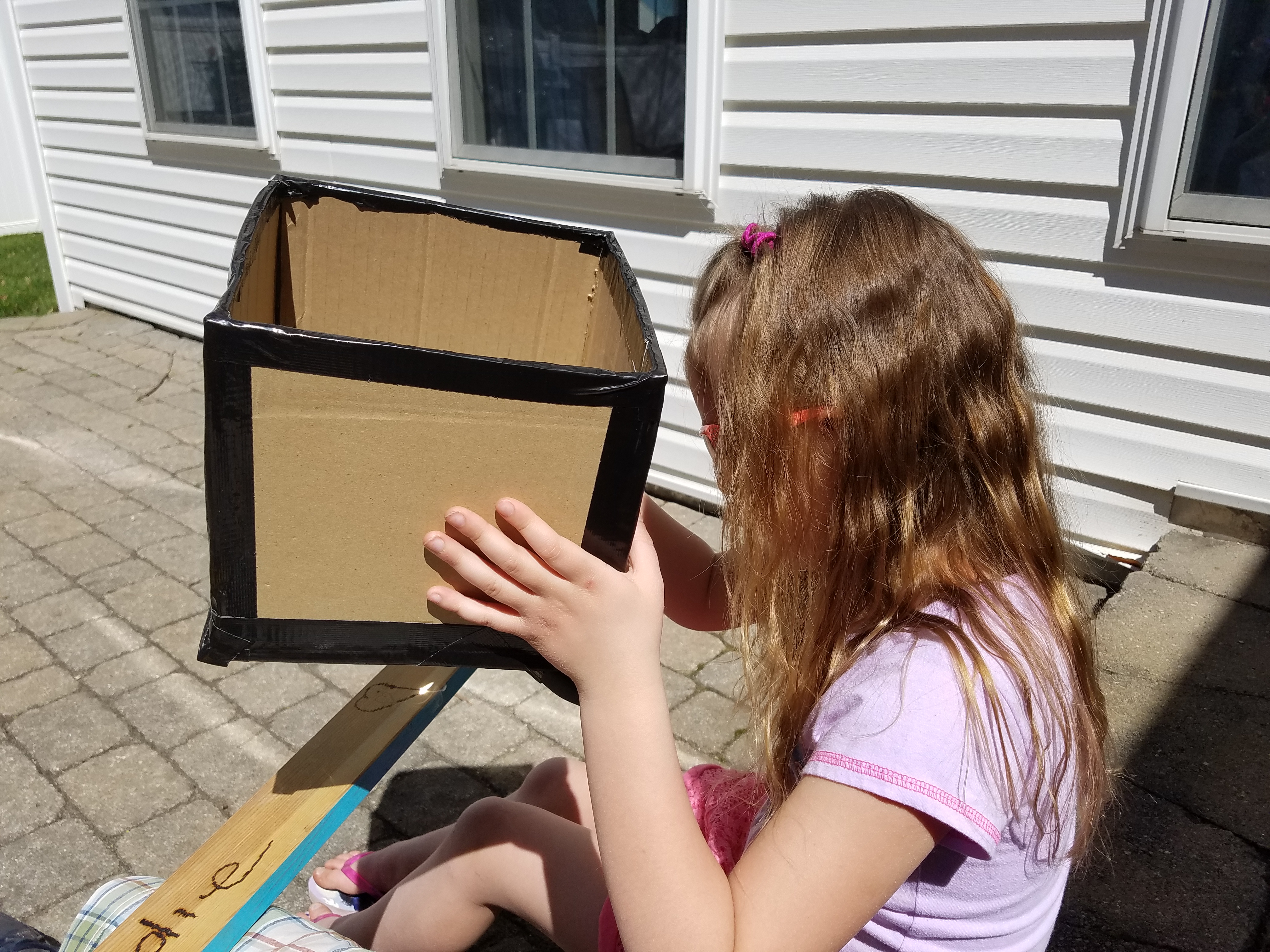 Using magnifying glass to burn her name on the back